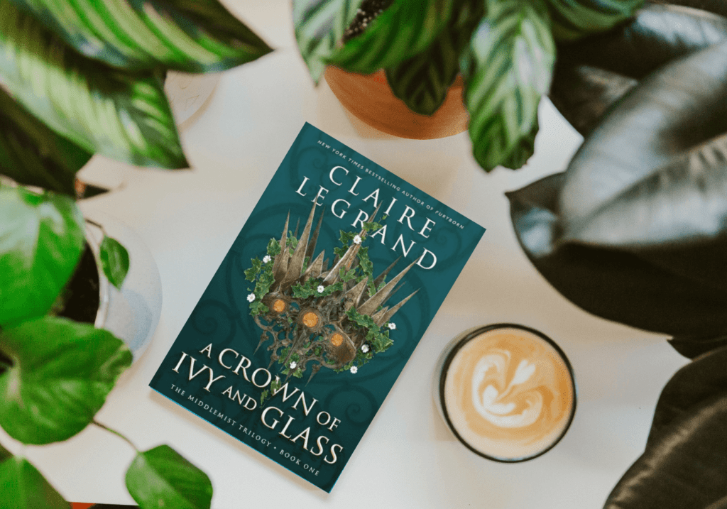 A Crown of Ivy and Glass by Claire Legrand with a coffee and plants