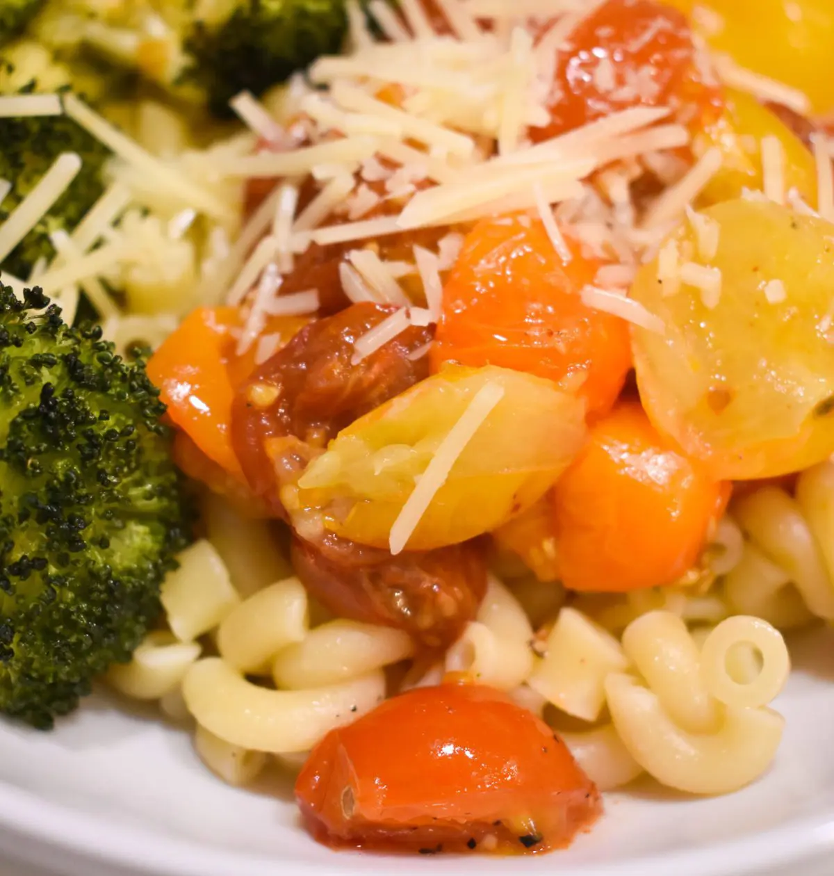Plated Pomodoro pasta with roasted broccoli and shredded parmesan cheese.