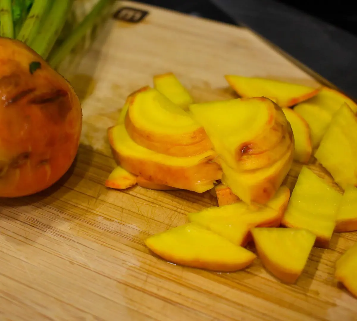 Diced golden beets and full golden beet on a cutting board.