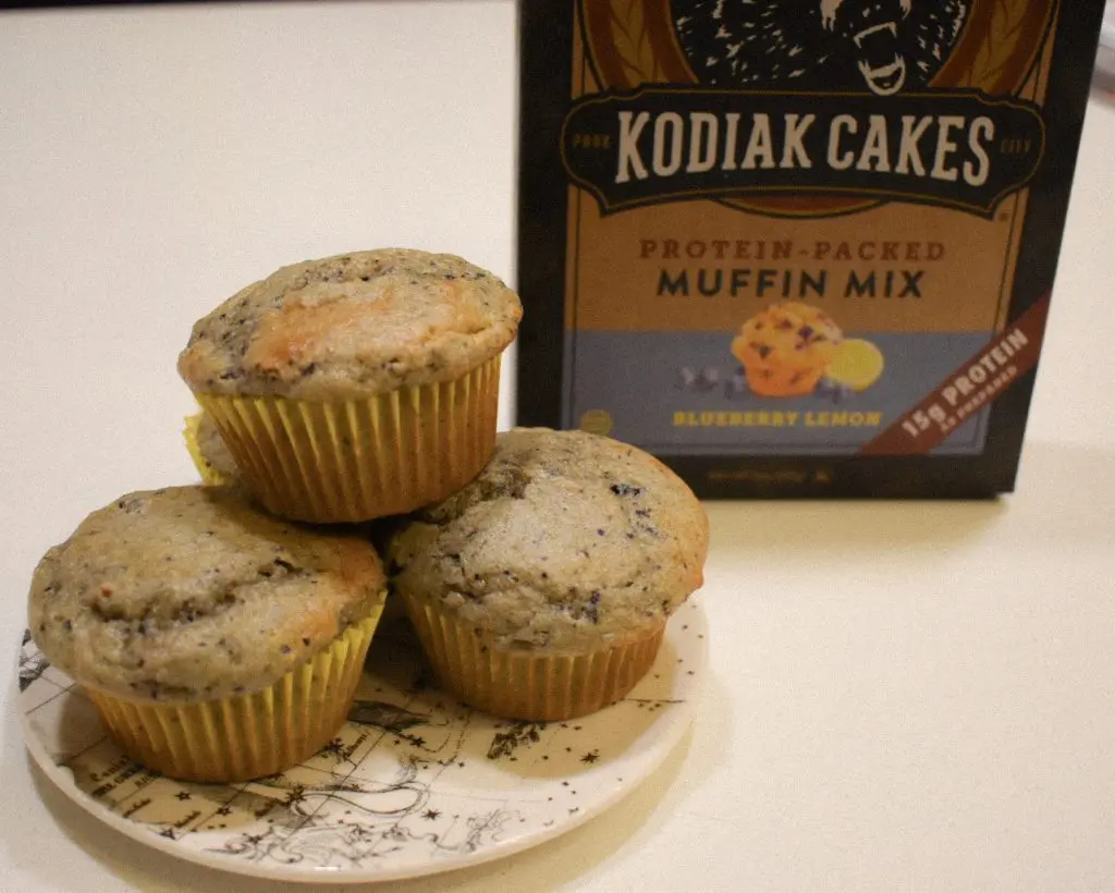 Kodiak Cake Muffin Mix - Cats & Coffee Kodiak Cakes Muffin Mix -- blueberry lemon flavor -- with a little Anthropologie plate of freshly baked muffins in yellow wrappers