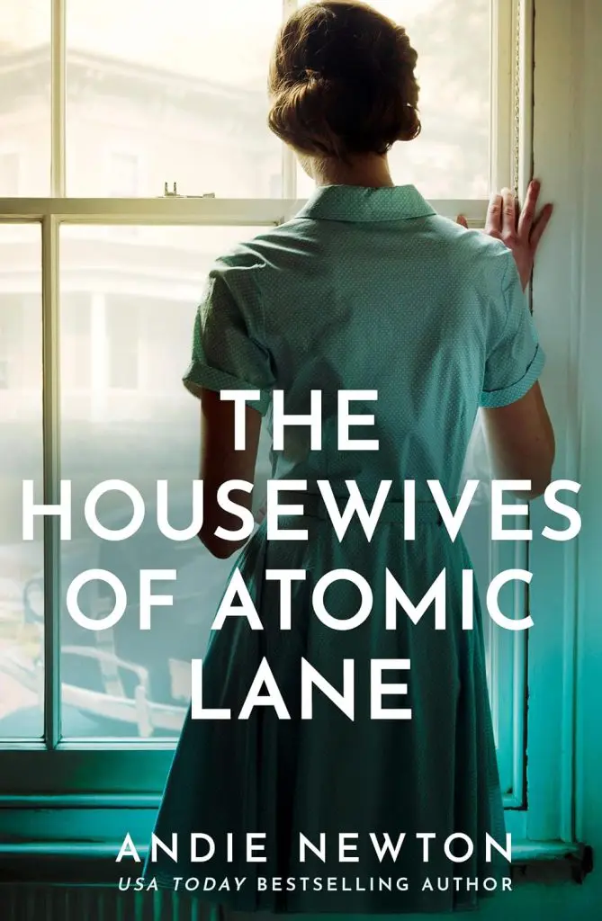 The Housewives of Atomic Lane by Andie Newton - Cats & Coffee Woman in a teal dress stands by a window, seen from behind, book title The Housewives of Atomic Lane prominently overlaid.