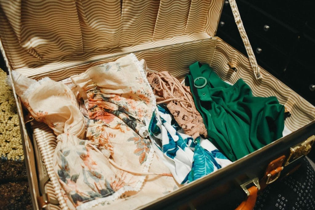 Steamline Luggage Suitcase with assorted summer styles, including Zimmermann, XIX Palms, Free People, and Solid and Striped