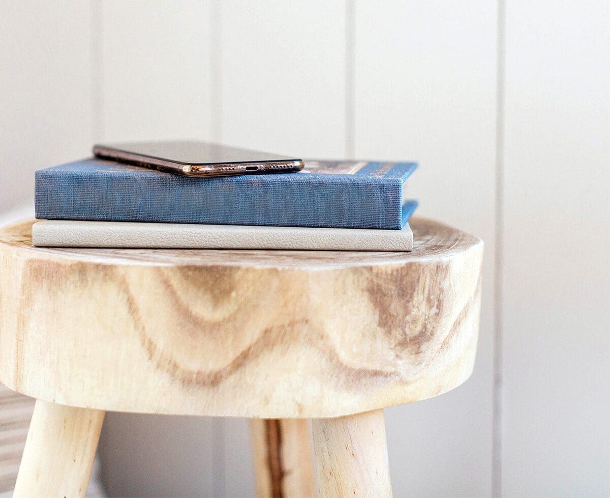 Phone and books on a light wood stool