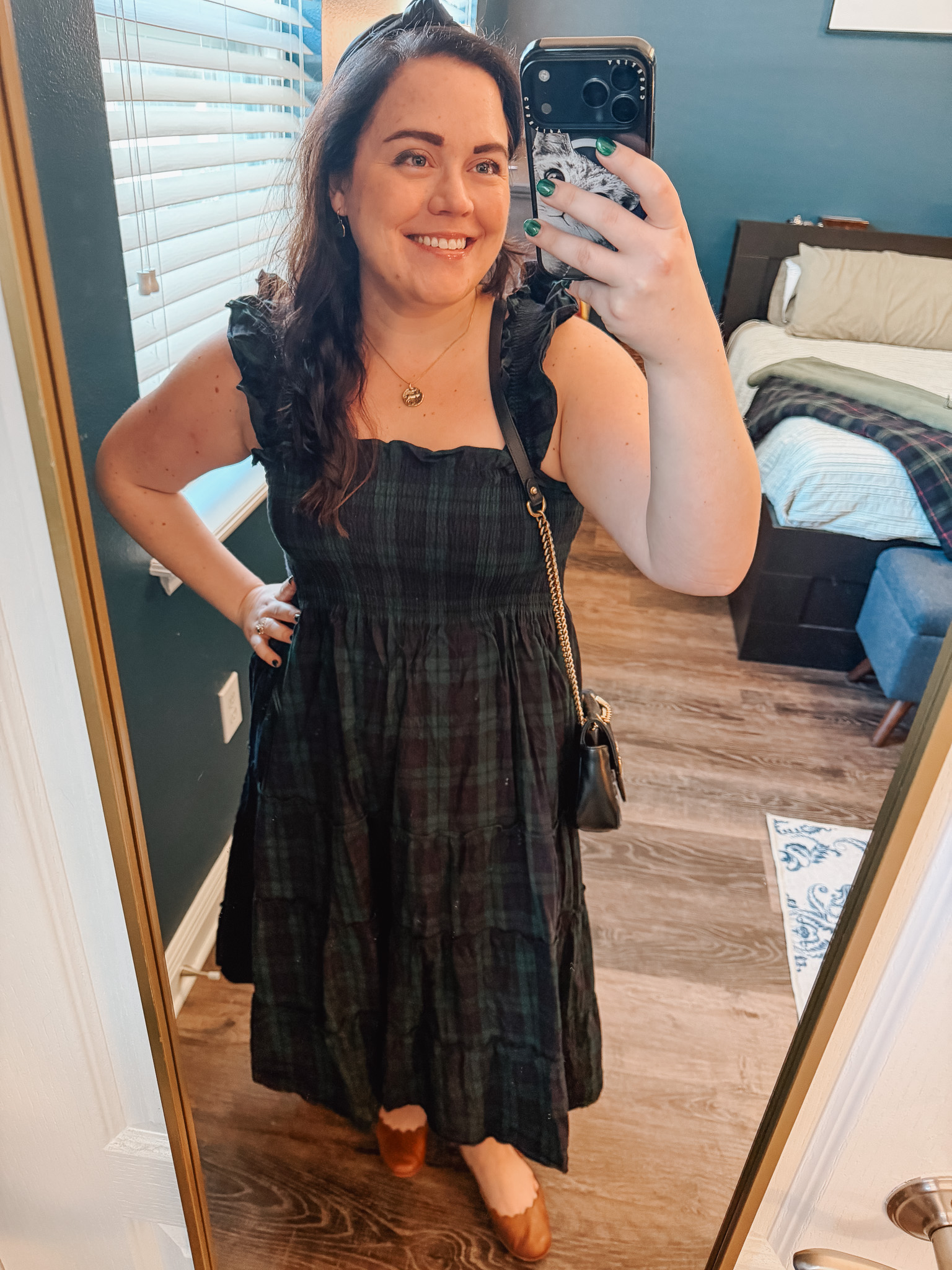 Festive-Tartan-Outfit-Ideas-7-Ways-to-Wear-Tartan-This-Holiday-Season-1webp - Cats & Coffee Woman wearing black and green tartan plaid midi dress with ruffle straps and crossbody bag — dressy holiday tartan outfit idea
