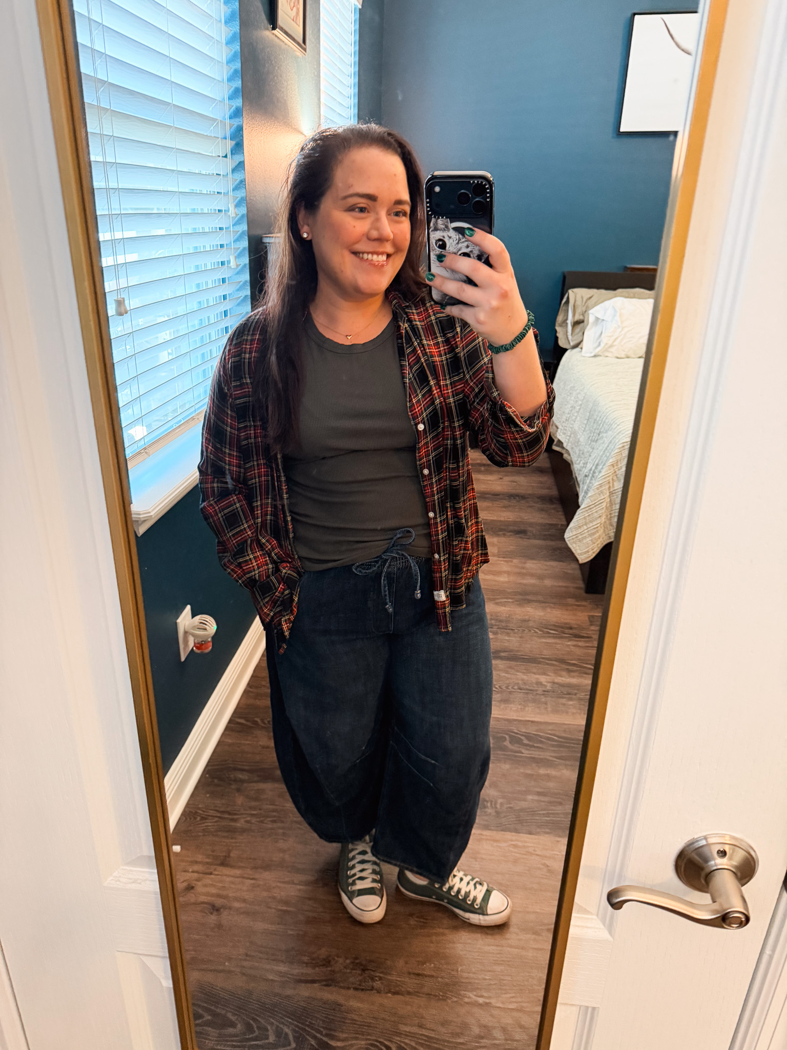 Festive-Tartan-Outfit-Ideas-7-Ways-to-Wear-Tartan-This-Holiday-Season-2webp - Cats & Coffee Woman wearing red and black tartan flannel shirt over black tee with jeans and Converse — casual tartan outfit for everyday wear