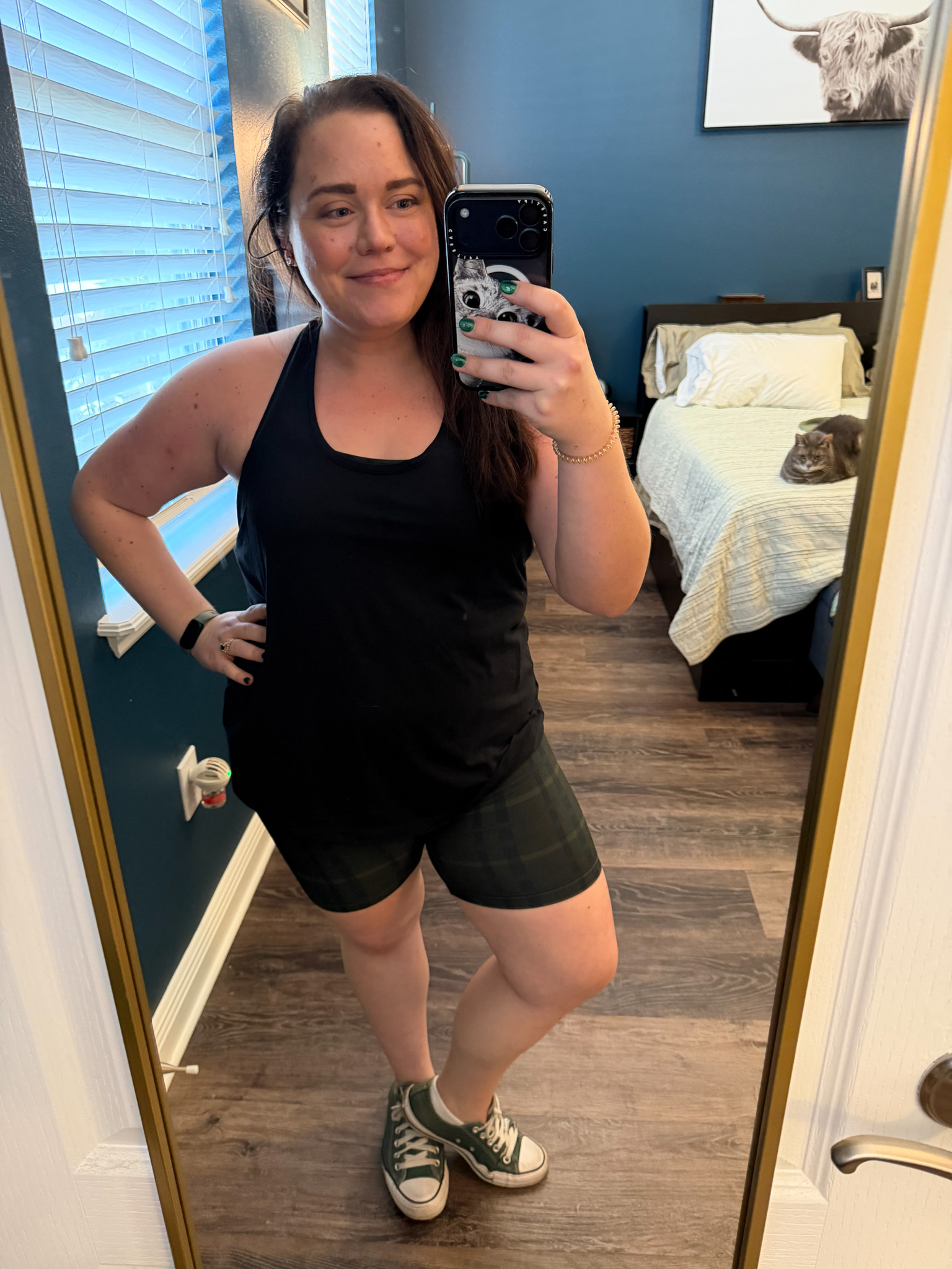 Festive-Tartan-Outfit-Ideas-7-Ways-to-Wear-Tartan-This-Holiday-Season-5webp - Cats & Coffee Woman wearing black tank top and green tartan bike shorts with green Converse sneakers for casual gym outfit