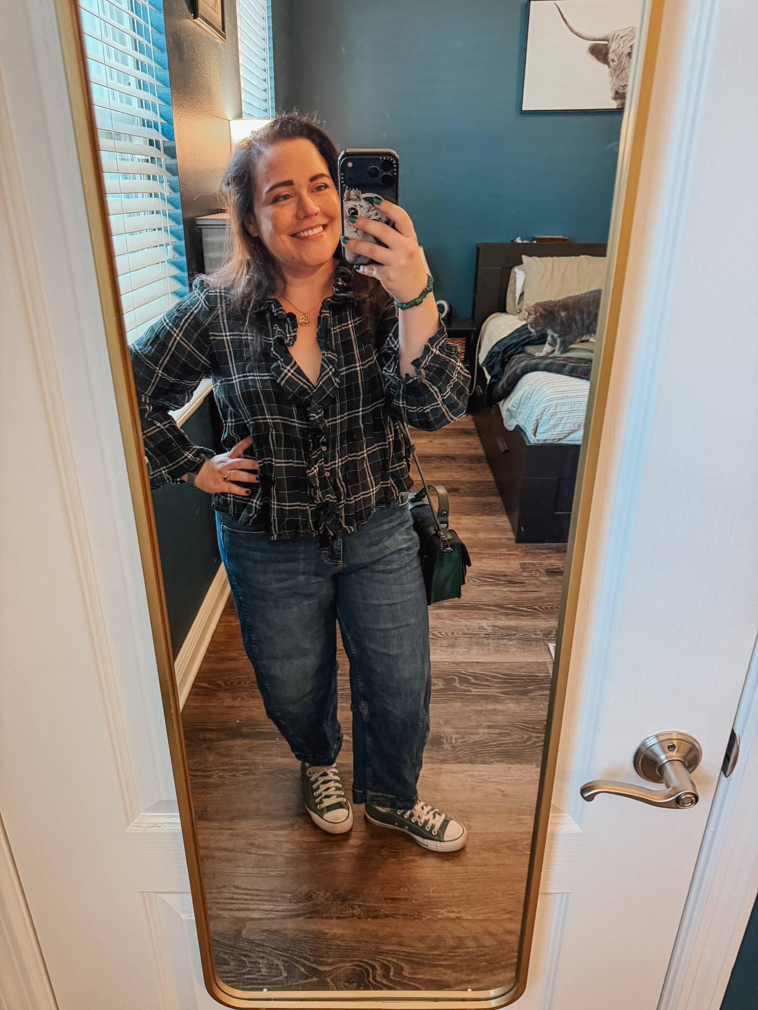 Festive-Tartan-Outfit-Ideas-7-Ways-to-Wear-Tartan-This-Holiday-Season-8webp - Cats & Coffee Woman wearing dark green, black, white tartan plaid button-up shirt with jeans and Converse — casual holiday tartan outfit with denim